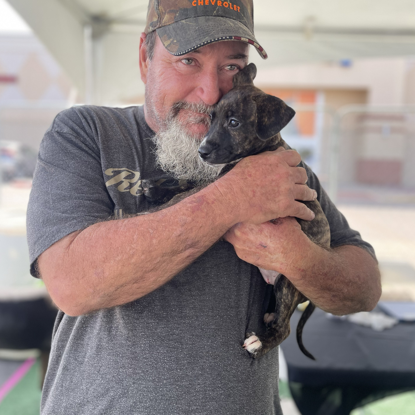 man cuddles puppy he's holding at an adoption event