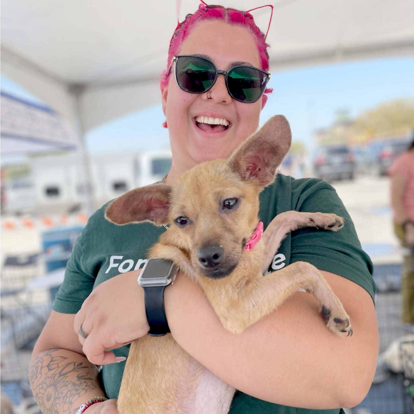 smiling woman looks at the camera, holding a dog in her arms