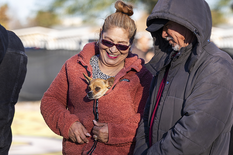 two pet parents smile down at a chihuahua snuggled in one of their jackets