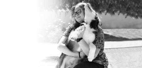 woman with glasses plays with husky